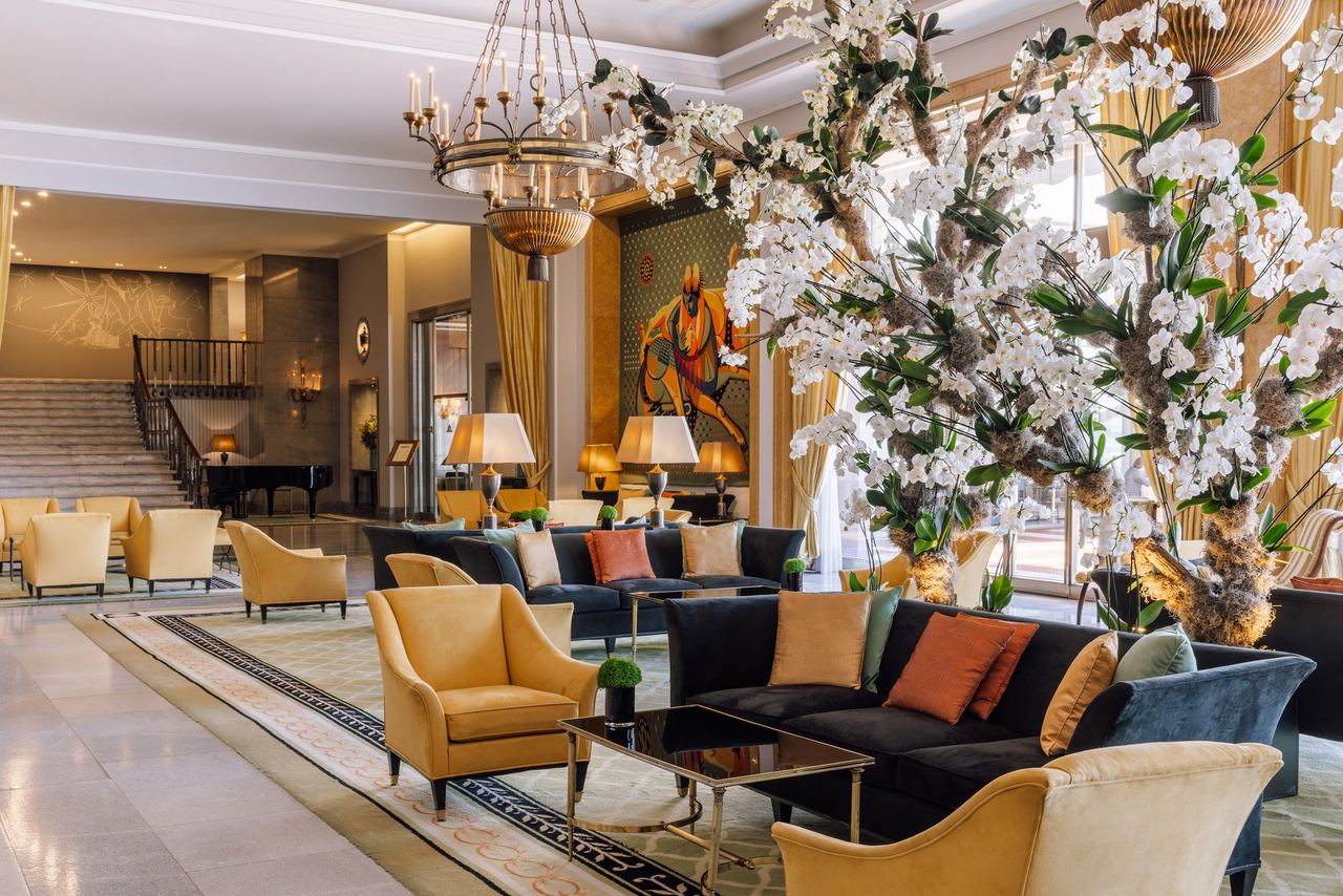 The lobby lounge of the Four Seasons Hotel Ritz Lisbon: velvet sofas, a tapestry, orchids and a sweeping staircase